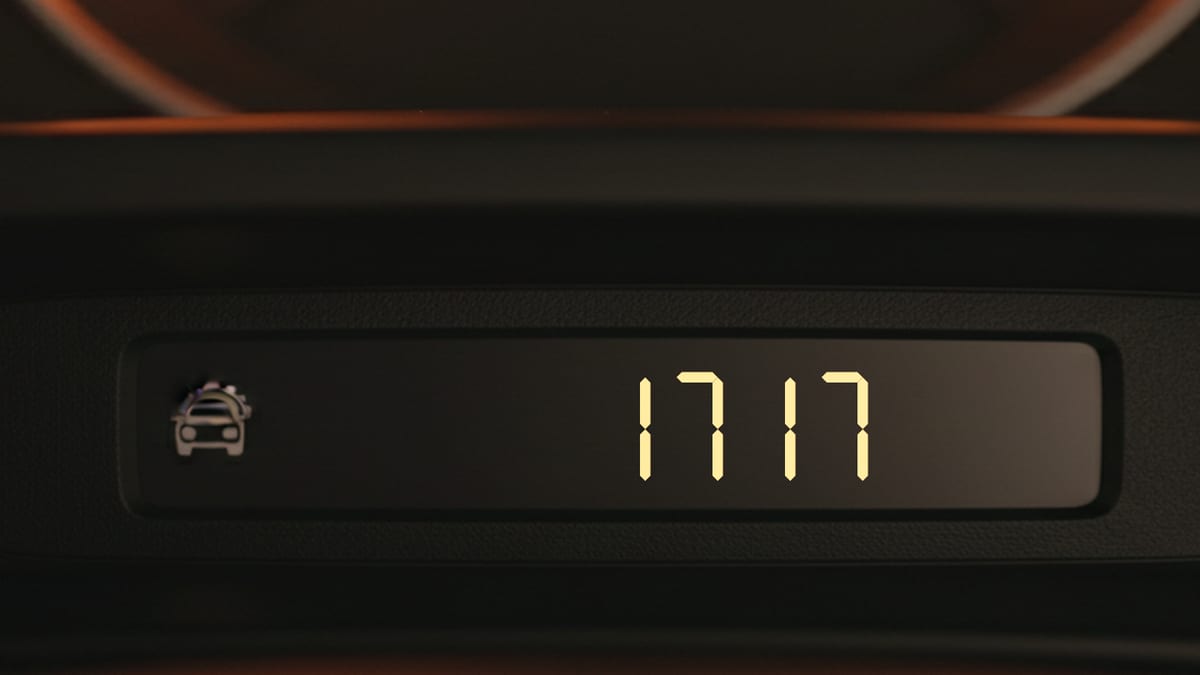 A car trip odometer glowing amber at night, reading 1717.